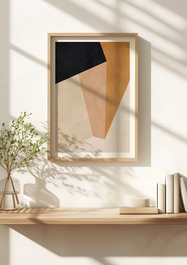 Een minimalistische houten plank met links een kleine potplant en rechts een stapel witte boeken. Boven de plank hangt een ingelijst CollageDepot Geometrisch Abstract Schilderij, beveiligd door een magnetisch ophangsysteem, met overlappende geometrische vormen in zwarte, bruine en beige tinten. Zonlicht werpt schaduwen op de muur.,Lichtbruin