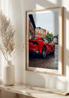 Aan de muur hangt een CollageDepot Rode Ferrari 812 Superfast Schilderij. Aan de linkerkant van het frame voegt een witte vaas met decoratieve gedroogde planten charme toe. De scène lijkt goed verlicht door natuurlijk licht en wordt veilig weergegeven met behulp van een magnetisch ophangsysteem.,Lichtbruin