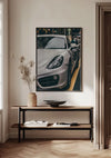 Een Nardo Grey Porsche 718 Schilderij van CollageDepot hangt aan een beige muur boven een minimalistische houten consoletafel. Op de tafel staat een arrangement met gedroogde planten, een lege kom en een open boek. De vloer heeft een visgraatmotief. De wanddecoratie wordt verlicht met natuurlijk licht.,Zwart