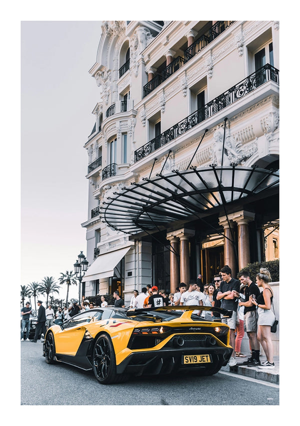 Een gele CollageDepot aaa 015 luxe sportwagen staat geparkeerd voor een sierlijk hotel en trekt de aandacht van een menigte mensen die hem bewonderen en foto's maken. De scène speelt zich af in een bruisend stedelijk gebied.-