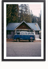 Een ingelijste foto van een vintage Volkswagen-bus, in klassiek blauw en wit, geparkeerd voor een klein huis met een grijs metalen dak. Het huis is omgeven door hoge bomen, wat een bosrijke omgeving suggereert. Dit rustige tafereel zorgt voor een perfecte wanddecoratie en kan eenvoudig worden tentoongesteld met een magnetisch ophangsysteem. Maak kennis met het Blauwe Volkswagenbus Schilderij van CollageDepot.,Zwart-Met,Lichtbruin-Met,showOne,Met