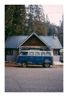 Een vintage blauw-witte Volkswagen-bus staat geparkeerd voor een kleine houten cabine met een metalen dak. Het busje vertoont tekenen van roest en slijtage en heeft bagagerekken op het dak. Hoge pijnbomen omringen de cabine en creëren een schilderachtig tafereel dat perfect is voor Blauwe Volkswagenbus Schilderij van CollageDepot.-