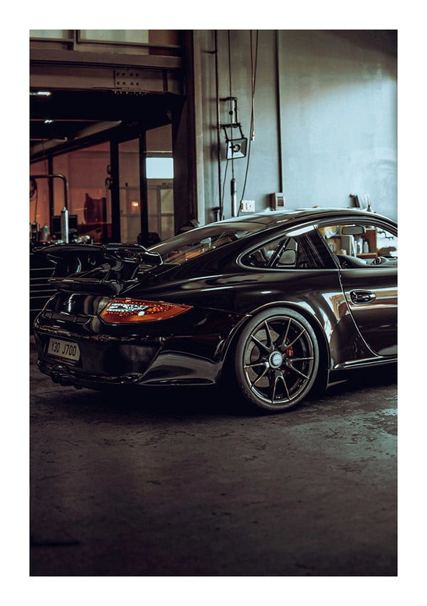 Een zwarte CollageDepot aaa 049 - auto staat geparkeerd in een slecht verlichte industriële garage en laat het strakke ontwerp en sportieve silhouet zien.-