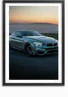Een ingelijste foto van een slanke zilveren BMW M3-auto, geparkeerd op een lege weg in de schemering met verlichte koplampen. De lucht op de achtergrond vertoont een verloop van lichtoranje nabij de horizon naar donkerdere tinten hogerop. Dit CollageDepot BMW M3 Bij zonsondergang Schilderij creëert een rustige, minimalistische esthetiek en is voorzien van een magnetisch ophangsysteem voor eenvoudige weergave.,Zwart-Met,Lichtbruin-Met,showOne,Met