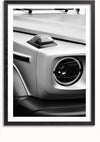 Een zwart-wit close-upfoto van de voorste hoek van een Mercedes G-wagen AMG, waarbij de koplamp en de richtingaanwijzer centraal staan. Het voertuig heeft een boxy, hoekig ontwerp met strakke details. Dit stijlvolle beeld, perfect voor wanddecoratie of als Mercedes G Wagon Voorkant Schilderij van CollageDepot, is omlijst met een eenvoudige zwarte rand.,Zwart-Met,Lichtbruin-Met,showOne,Met