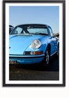 Er wordt een ingelijste foto getoond van een vintage blauwe Porsche 911. De auto heeft ronde koplampen en een opvallend frontontwerp. De auto is vastgelegd vanuit een frontale hoek, geparkeerd op een zwart asfaltoppervlak onder een helderblauwe lucht. Het Vintage Porsche 911 Schilderij van CollageDepot is ideaal als wanddecoratie en beschikt over een eenvoudig te gebruiken magnetisch ophangsysteem.,Zwart-Met,Lichtbruin-Met,showOne,Met