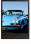 Een ingelijste foto van een vintage blauwe Porsche 911, waarschijnlijk een klassiek model, buiten geparkeerd. De auto heeft een afgerond koplampontwerp en een zichtbare grill, met een zwarte kentekenplaat aan de voorzijde. De heldere lucht op de achtergrond draagt bij aan de charme. Perfecte wanddecoratie met magnetische ophangsysteemmogelijkheden, verkrijgbaar als het Vintage Porsche 911 Schilderij van CollageDepot.,Zwart-Zonder,Lichtbruin-Zonder,showOne,Zonder