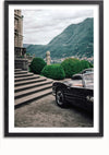 Een ingelijste foto toont een klassieke BMW-cabrio, geparkeerd vlakbij de trappen van een elegant gebouw. Weelderige groene struiken en bergen zijn op de achtergrond te zien onder een bewolkte hemel, waardoor dit Klassieke BMW Cabrio Schilderij van CollageDepot een voortreffelijk stukje wanddecoratie is.,Zwart-Met,Lichtbruin-Met,showOne,Met