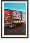 Een klassieke rode auto staat geparkeerd in een straat voor een kleurrijke muurschildering met verschillende gezichten en abstracte ontwerpen. De lucht is helder en de auto en de muurschildering zijn beide prominent in de lijst weergegeven. De muurschildering, genaamd Red Passion Schilderij van CollageDepot, bevat teksten als "DRACULA" en "FRANK", verwijzend naar iconische horrorfilmpersonages.,Zwart-Met,Lichtbruin-Met,showOne,Met