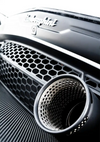 Close-up van de grille en uitlaatpijp van een zwarte sportwagen, waarbij de texturen van de metalen en koolstofvezeloppervlakken worden benadrukt, met het logo "CollageDepot Carrera GT" zichtbaar.-