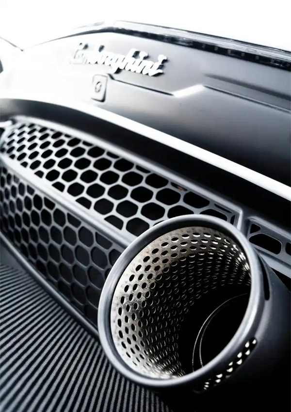 Close-up van de grille en uitlaatpijp van een zwarte sportwagen, waarbij de texturen van de metalen en koolstofvezeloppervlakken worden benadrukt, met het logo "CollageDepot Carrera GT" zichtbaar.-