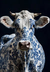 Een koe met witte vacht, geheel beschilderd met ingewikkelde blauwe bloemmotieven, staat tegen een donkere achtergrond, recht naar de camera gericht. Het Delfts Blauw Koe Schilderij van CollageDepot lijkt gemaakt van porselein. Dit unieke stuk zorgt voor opvallende wanddecoratie.