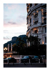 Een luxueus gebouw met meerdere verdiepingen, verlicht in de schemering met een bergachtige achtergrond, lijkt op een meesterwerk. Voor het gebouw staan meerdere auto's, waaronder enkele luxe modellen, geparkeerd. Straatlantaarns verlichten het trottoir en de entree, wat bijdraagt aan het schilderachtige schilderijgevoel van Hotel de Paris by night, gecreëerd door CollageDepot.