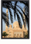 Afbeelding van een moskee met twee minaretten en een grote centrale koepel, gezien door overhangende palmbladeren. De moskee, die doet denken aan een prachtig schilderij, is gemaakt van lichtgekleurde steen en steekt af tegen een helderblauwe lucht. De palmbladeren op de voorgrond vormen een natuurlijk kader voor deze prachtige wanddecoratie, het "Moskee Met Sierlijke Structuur Schilderij" van CollageDepot.,Zwart-Zonder,Lichtbruin-Zonder,showOne,Zonder