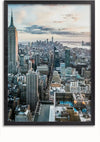 Luchtfoto van New York City met talloze wolkenkrabbers, waaronder het Empire State Building aan de linkerkant. De scène toont een mix van hoge gebouwen, straten en een gedeeltelijk bewolkte lucht bij zonsondergang - ideaal voor een schilderij met uitzicht op New York van CollageDepot, perfect als wanddecoratie met een magnetisch ophangsysteem.