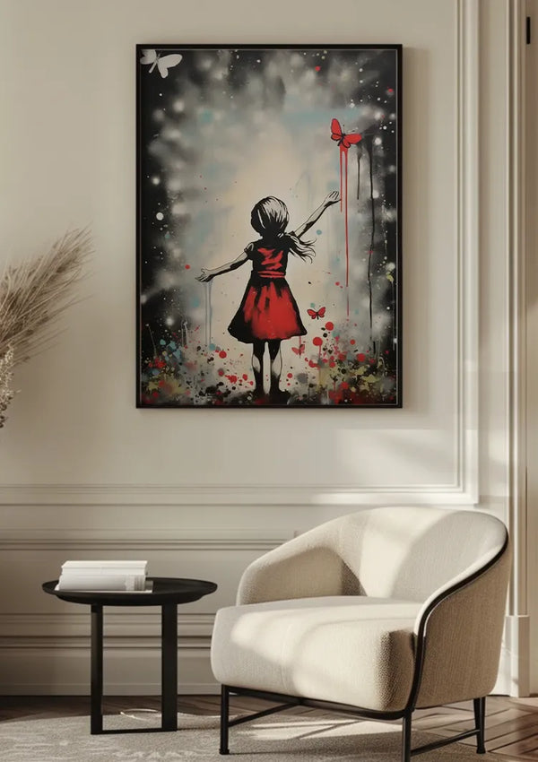 Een ingelijst Meisje Reikt Naar Vlinders Schilderij van CollageDepot, met de rug van een meisje in een rode jurk die met haar linkerhand naar een rode vlinder reikt, omgeven door abstracte kleurspatten, is aan de muur gemonteerd boven een witte fauteuil en een kleine zwarte bijzettafel in een goed verlichte kamer.,Zwart