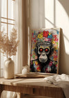 Op een houten tafel bij een raam staat een kleurrijk schilderij in graffitistijl, voorstellende een aap met rode ogen. Op tafel staan ook een beige vaas met droogbloemen en een witte deken, wat een gezellige en kunstzinnige sfeer creëert. Deze levendige wanddecoratie, het Zwart En Wit Apen Gezicht Schilderij van CollageDepot, voegt moeiteloos charme toe aan de kamer.,Lichtbruin