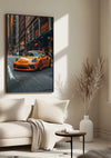 Een minimalistische woonkamer met een beige bank, een deken, een ronde salontafel en een decoratieve vaas met gedroogde planten. Op de beige muur is een prachtig Levendig Oranje Porsche Schilderij van CollageDepot te zien van een oranje sportwagen in een stadsstraat. Zonlicht stroomt door een nabijgelegen raam en versterkt de elegante wanddecoratie.,Zwart