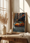 Een ingelijste foto van een oranje sportwagen in een stadsstraat leunt tegen een muur op een houten tafel en toont het Vibrant Orange Porsche Schilderij van CollageDepot. Op de tafel staat ook een witte vaas met gedroogde planten, een kleine kruik en een opgevouwen doek, allemaal bij een raam geplaatst waar het licht door vitrages naar binnen filtert.,Lichtbruin