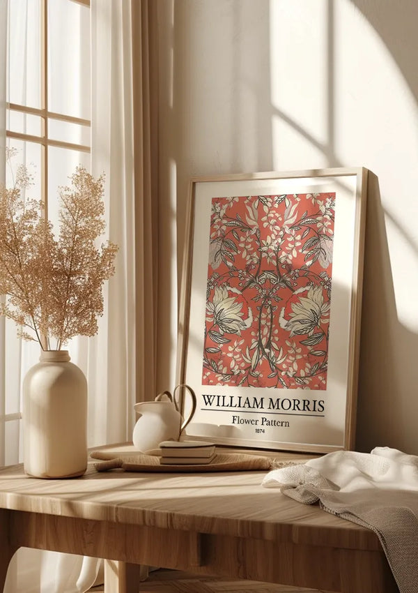 Een ingelijst W. Morris Flower Pattern Schilderij van CollageDepot rust op een houten tafel. Op de tafel staat ook een vaas met gedroogde bloemen, een kopje en een boek. Zonlicht filtert door transparante gordijnen, waardoor een heldere en warme sfeer ontstaat.,Lichtbruin