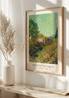 Aan de muur hangt een ingelijst V. Van Gogh Landschap Schilderij van CollageDepot met een levendig landschap met een klein huis, kleurrijke bloemen en weelderig groen. Het beeld baadt in natuurlijk licht, met decoratief pampasgras in een vaas op een witte houten plank ernaast, met behulp van een magnetisch ophangsysteem.,Lichtbruin