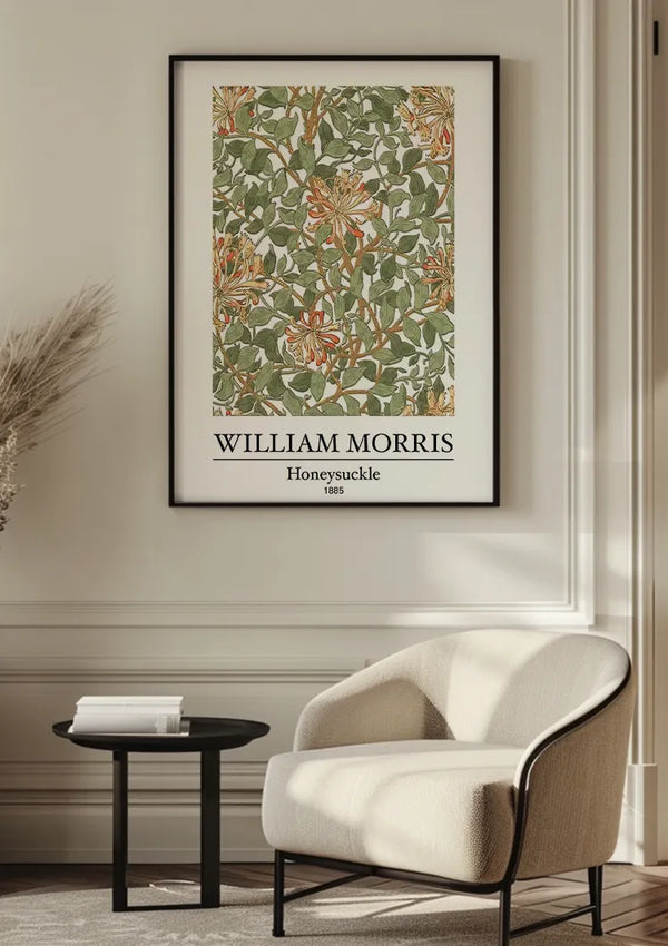 Een ingelijst kunstwerk van CollageDepot met de titel "W. Morris Honeysuckle Schilderij" wordt op een muur boven een witte, moderne stoel getoond. Naast de stoel staat een klein zwart bijzettafeltje met een boek erop. De setting, geaccentueerd door het botanische patroon van het stuk, straalt met zijn neutrale tinten eigentijdse elegantie uit.,Zwart