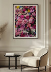 Een moderne, minimalistische kamer met een witte fauteuil, een klein zwart rond bijzettafeltje en het Roze Bloemen Schilderij van CollageDepot met een groot ingelijst bloemkunstwerk aan de muur. De wanddecoratie toont levendige roze, witte en geelroze lelies. In de hoek is een gevederde plant zichtbaar.,Zwart