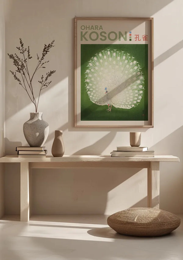 Een minimalistische kamer met een houten bank met vazen en een kussen. Boven de bank hangt een CollageDepot-schilderij met de titel "O. Koson Peacock Print Schilderij", met een witte pauw op een groene achtergrond. Zonlicht werpt zachte schaduwen over de muur en wanddecoratie, versterkt door het magnetische ophangsysteem.,Lichtbruin