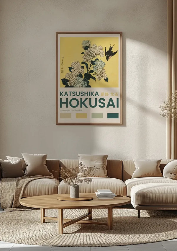 Een gezellige woonkamer met een beige kleurenschema is voorzien van een ingelijst kunstwerk van bloemen en een vogel, met het opschrift "K. Hokusai Hydrangea And Swallow Schilderij" van CollageDepot, dat aan de muur hangt met behulp van een magnetisch ophangsysteem. De kamer is voorzien van een ronde houten salontafel, een beige bank met witte en beige kussens en gedroogde bloemen in een vaas.,Lichtbruin